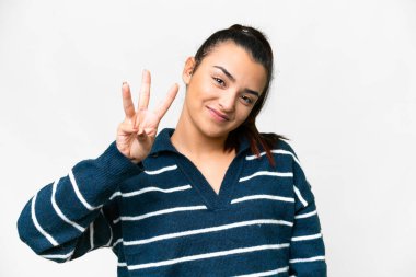 Soyutlanmış beyaz arka planda genç bir kadın mutlu ve parmaklarıyla üçe kadar sayıyor.