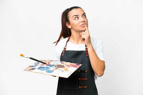 孤立した白い背景の上にパレットを保持する若い芸術家の女性は疑問を持ちながら検索 — ストック写真