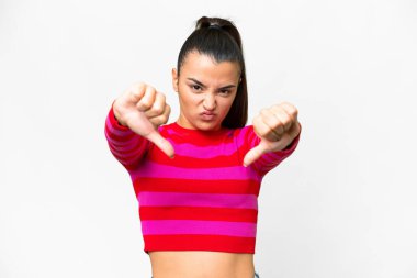 İzole edilmiş beyaz arka planda genç bir kadın baş parmağını iki eliyle aşağı gösteriyor.