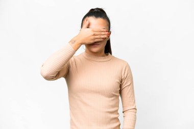 İzole edilmiş beyaz arka planı olan genç, güzel bir kadın gözlerini elleriyle kapatıyor. Bir şey görmek istemiyorum.