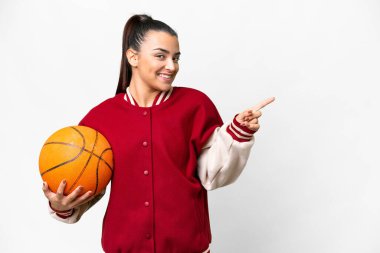 İzole edilmiş beyaz arka planda basketbol oynayan genç bir kadın parmak kaldırıyor.