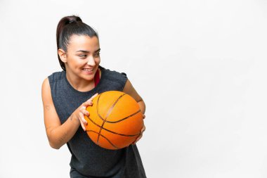 Soyutlanmış beyaz arka planda basketbol oynayan genç bir kadın.