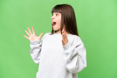 Yüzünde sürpriz bir ifade olan izole edilmiş yeşil renkli anahtar arka planı olan küçük bir kız.