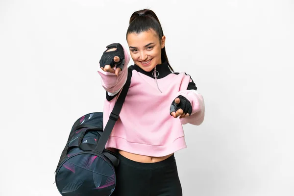 Young sport woman with sport bag over isolated white background points finger at you while smiling
