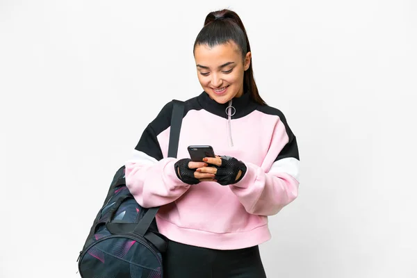 stock image Young sport woman with sport bag over isolated white background sending a message with the mobile