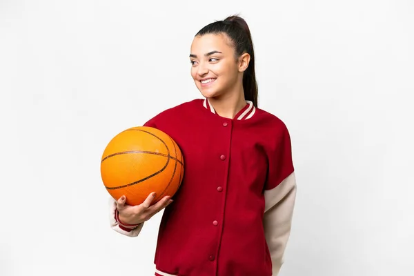 若いです女性プレイバスケットボール上の隔離された白い背景見ますへ側と笑顔 — ストック写真