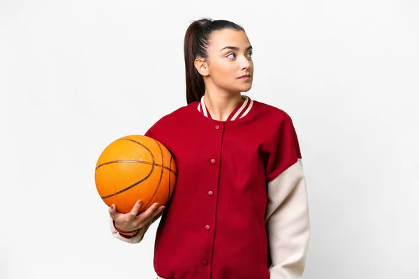 若いです女性プレイバスケットボール上の隔離された白い背景見ますザ側 — ストック写真