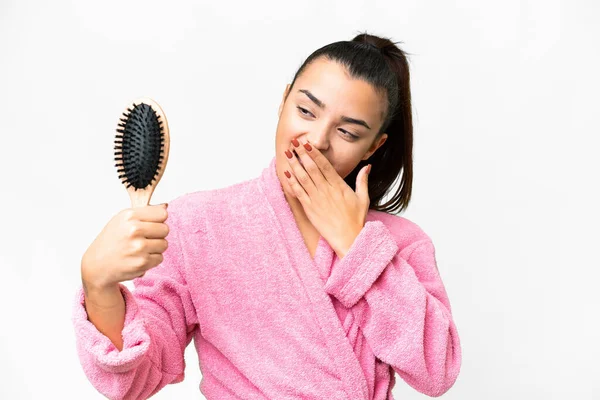 Young woman in a bathrobe with hair comb over isolated white background with surprise and shocked facial expression