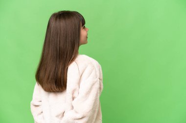 Küçük kız izole edilmiş yeşil krom anahtar arka planda ve geriye bakıyor