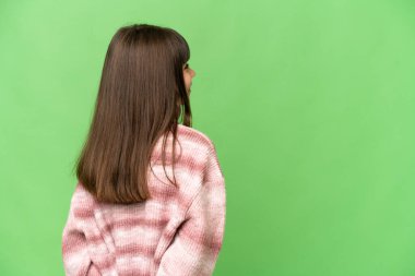 Küçük kız izole edilmiş yeşil krom anahtar arka planda ve geriye bakıyor