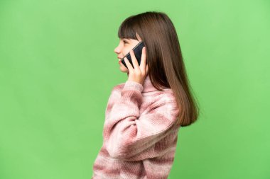 İzole edilmiş yeşil renkli anahtar geçmişi olan küçük bir kız cep telefonuyla sohbet ediyor.