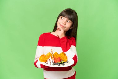 İzole edilmiş krom arka planda waffle tutan küçük bir kız.