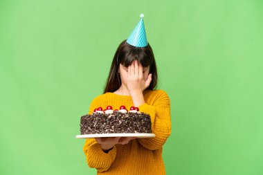 Küçük kız elinde doğum günü pastası ile izole edilmiş krom anahtar arka planda yorgun ve hasta bir ifadeyle