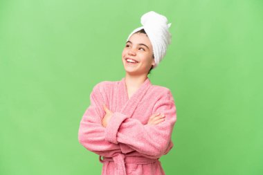 Üzerinde bornoz olan küçük bir kız izole edilmiş krom anahtar arka planda mutlu ve gülümsüyor.