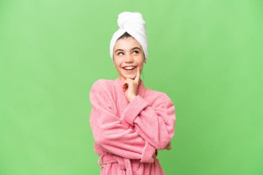 İzole edilmiş krom anahtar geçmişi olan bornozlu küçük bir kız yukarı bakarken bir fikir düşünüyor.