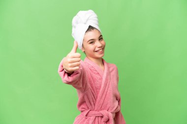 İzole edilmiş krom anahtar geçmişi olan bornozlu küçük bir kız. Başparmakları havada çünkü iyi bir şey oldu.