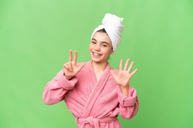 İzole edilmiş krom anahtar geçmişi olan bornozlu küçük bir kız parmaklarıyla sekiz tane sayıyor.