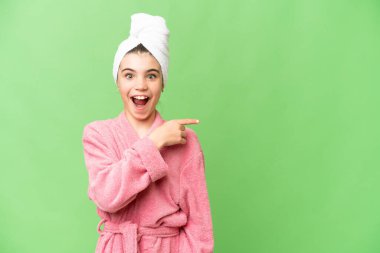 İzole edilmiş bir krom üzerine bornoz giymiş küçük bir kız. Arka planı şaşırmış ve işaret ediyor.