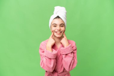 İzole edilmiş krom arka planda bornozlu küçük kız mutlu ve hoş bir ifadeyle gülümsüyor.