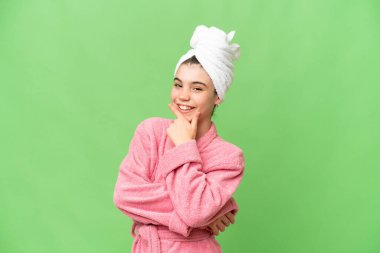 İzole edilmiş krom arka planda bornozlu küçük kız gülümsüyor.