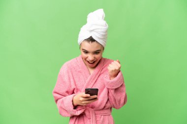 Bornozlu küçük bir kız izole edilmiş krom anahtar arka planı şaşırdı ve bir mesaj gönderiyor.