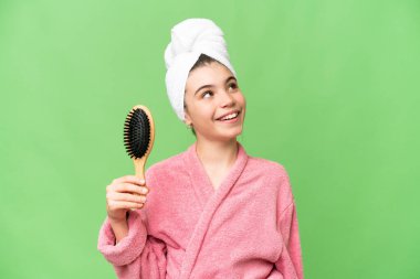 Saçları taranmış genç bir kız gülümserken yukarı bakıyor.