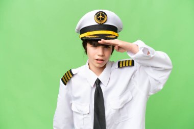 Küçük bir kız uçak pilotu olarak izole edilmiş bir krom anahtar arka planı var. Bir şeye bakmak için çok uzaklara bakıyor.