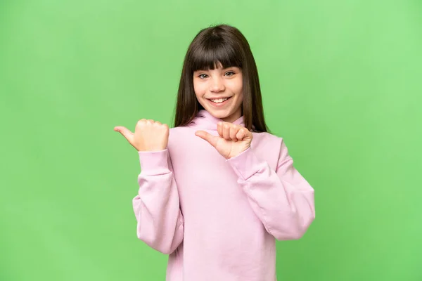 stock image Little girl over isolated green chroma key background pointing to the side to present a product