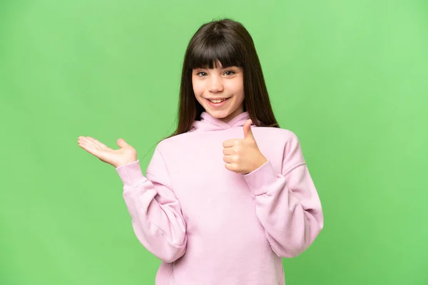 小女孩翻过孤立的绿色彩色键背景 手掌上握着想象的复制空间 插入广告 竖起大拇指 — 图库照片