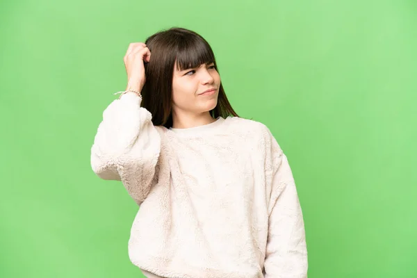 stock image Little girl over isolated green chroma key background having doubts while scratching head