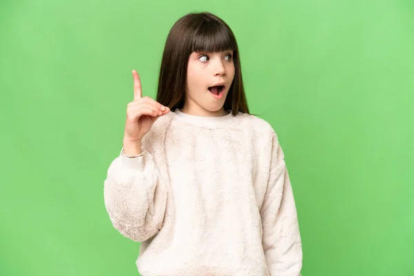 指を持ち上げながら解決策を実現しようとしている隔離された緑のクロマキー背景上の小さな女の子 — ストック写真