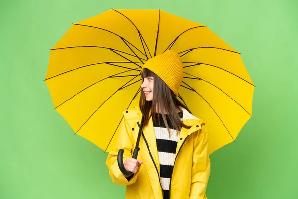 무지개 코트와 우산을 소녀가 배경을 바라본다 — 스톡 사진