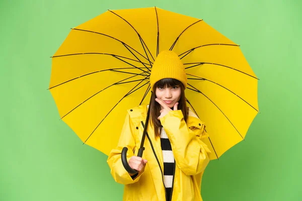 小さな女の子とともにレインプルーフコートと傘上の隔離されたクロマキー背景思考 — ストック写真