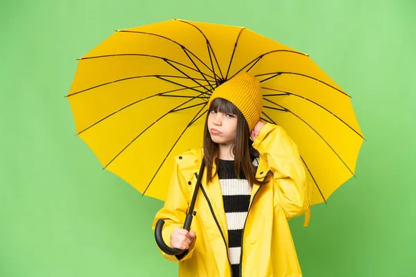 小さな女の子とともにレインプルーフコートと傘上の隔離されたクロマキー背景持っています疑問 — ストック写真