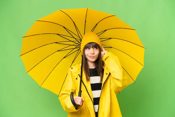 小さな女の子ともにレインプルーフコートと傘上の隔離されたクロマキー背景持っている疑問と思考 — ストック写真
