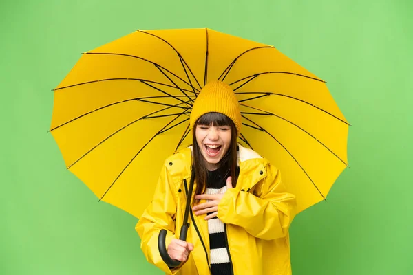 小さな女の子とともにレインプルーフコートと傘上の隔離されたクロマキー背景笑顔多くの — ストック写真