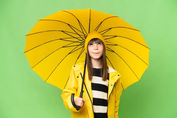 小さな女の子とともにレインプルーフコートと傘上の隔離されたクロマキー背景と見上げます — ストック写真