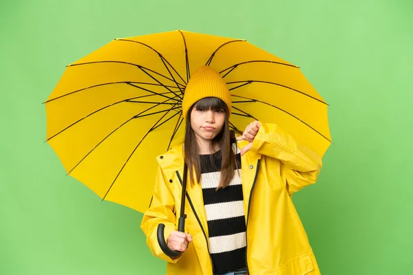 코트와 우산을 소녀가 엄지손가락을 아래로 부정적 표현을 — 스톡 사진