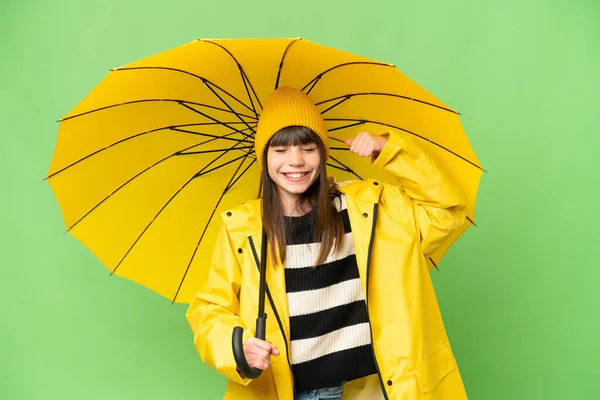 若いです女の子とともにレインプルーフコートと傘上の隔離されたクロマキー背景行います強いジェスチャー — ストック写真