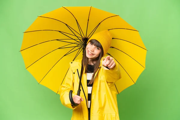 小さな女の子とともにレインプルーフコートと傘上の隔離されたクロマキー背景ポインティングフロントで幸せな式 — ストック写真