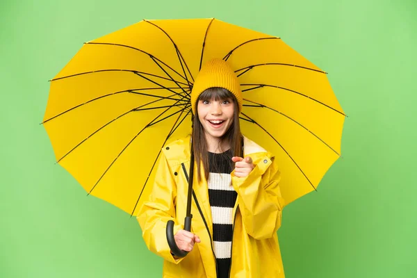 小さな女の子とともにレインプルーフコートと傘上の隔離されたクロマキー背景驚きと指す前 — ストック写真