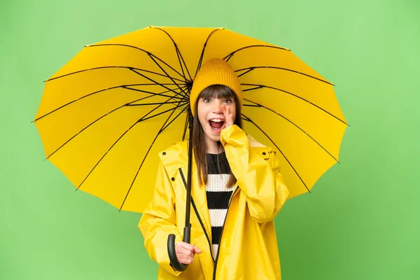 小さな女の子とともにレインプルーフコートと傘上の隔離されたクロマキー背景とともに驚きとショックを受けた顔の表情 — ストック写真