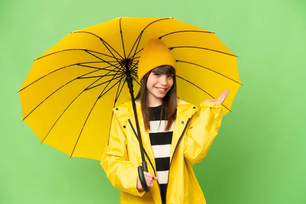 小さな女の子ともにレインプルーフコートと傘上の隔離されたクロマキーバック拡張手へザ側への招待 — ストック写真