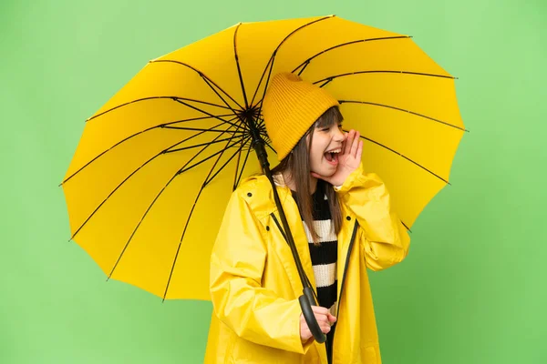 小さな女の子とともにレインプルーフコートと傘上の隔離されたクロマキー背景叫びますとともに口を開けて横に — ストック写真