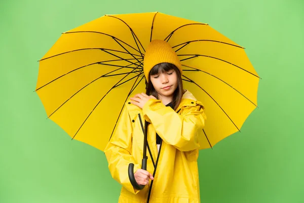小さな女の子ですレインプルーフコートと傘上の隔離されたクロマキー背景痛みに苦しんで肩のために努力をした — ストック写真