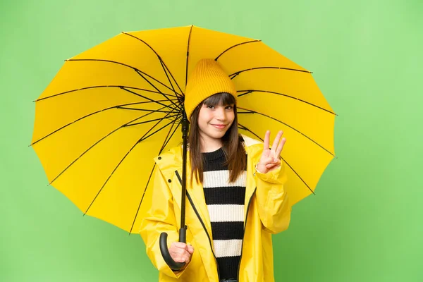 小さな女の子とともにレインプルーフコートと傘上の隔離されたクロマキー背景幸せとカウント3とともに指 — ストック写真