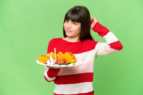 stock image Little girl holding waffles over isolated chroma key background having doubts