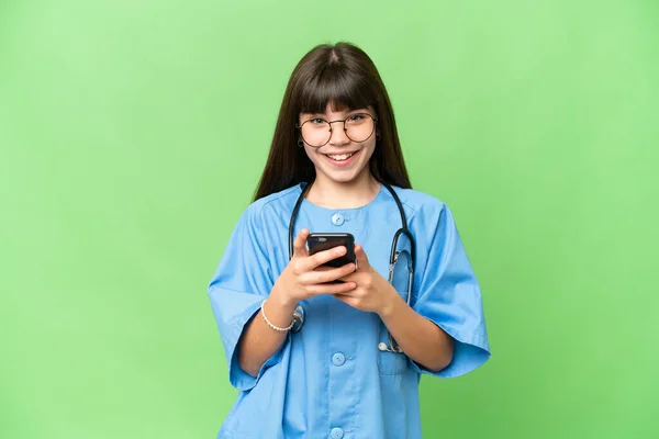 stock image Little girl as a surgeon doctor over isolated chroma key background sending a message with the mobile