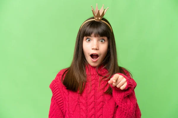 stock image Little princess with crown over isolated chroma key background surprised and pointing front