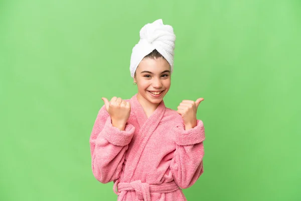 stock image Little girl in a bathrobe over isolated chroma key background with thumbs up gesture and smiling